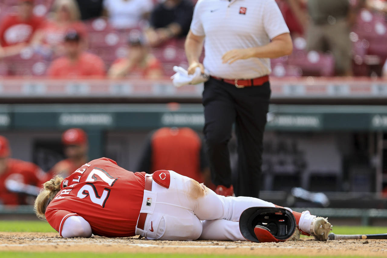 Cincinnati Reds' Jake Fraley lies on the ground after being hit by a pitch during the eighth inning...