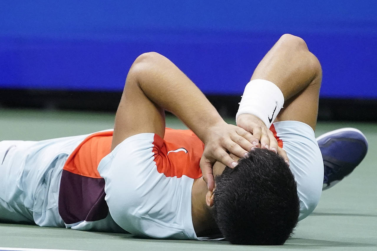 Carlos Alcaraz, of Spain, lays on the court after defeating Frances Tiafoe, of the United States, d...