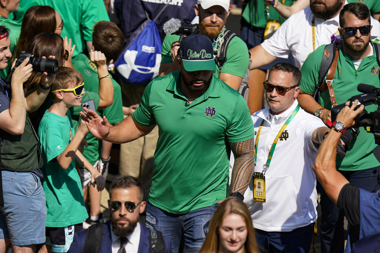Former Notre Dame player Manti Te'o follows members of the Notre Dame football team walk through th...