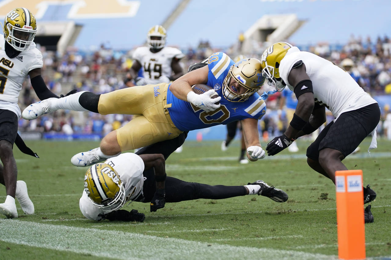 UCLA running back Carsen Ryan (20) is tackled by Alabama State defensive back James Burgess (27) an...