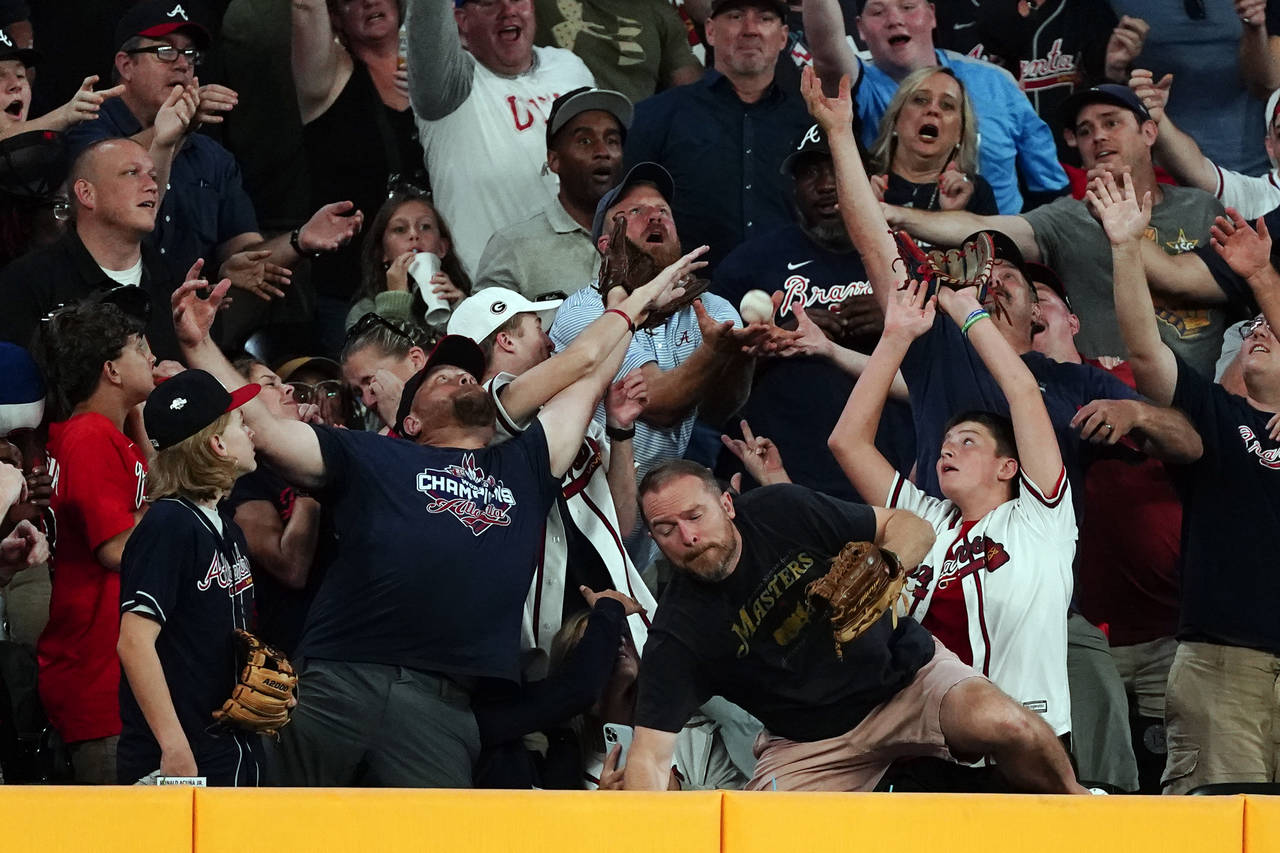 Fans reach for a ball hit for a two-run home run by Atlanta Braves' Vaughn Grissom in the fourth in...