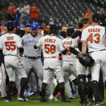 
              Baltimore Orioles relief pitcher Bryan Baker (43) is restrained by Baltimore Orioles catcher Adley Rutschman as both teams benches clear during the seventh inning a baseball game, Tuesday, Sept. 6, 2022, in Baltimore. (AP Photo/Terrance Williams)
            