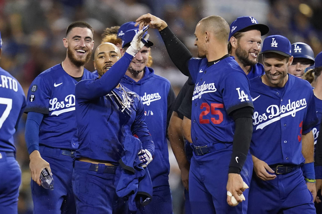 Los Angeles Dodgers' Mookie Betts, center, is greeted by Trayce Thompson (25) and other teammates a...