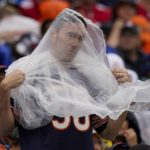 
              A fan tries to stay dry during the first half of an NFL football game between the Chicago Bears and the San Francisco 49ers Sunday, Sept. 11, 2022, in Chicago. (AP Photo/Nam Y. Huh)
            