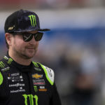 
              FILE - Driver Kurt Busch smiles while walking onto pit road prior to a NASCAR Cup Series auto racing race at Charlotte Motor Speedway, Sunday, Oct. 10, 2021, in Concord, N.C. Busch announced Saturday, Oct. 15, 2022,  he will miss the rest of this season with a concussion and will not compete full-time in 2023.  The 44-year-old made his announcement at Las Vegas Motor Speedway, his home track and where he launched his career on the bullring as a child. He choked up when he said doctors told him “it is best for me to ‘shut it down.'”  (AP Photo/Matt Kelley, File)
            