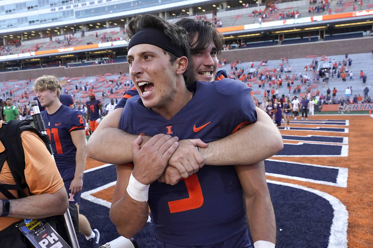 FILE - Illinois quarterback Tommy DeVito is hugged by a teammate after their win over Wyoming in an...