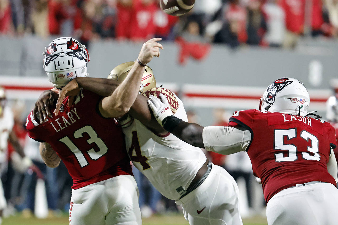 North Carolina State quarterback Devin Leary (13) is hit by Florida State's Joshua Farmer (44) whil...