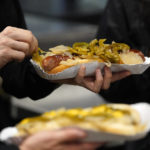 
              A baseball fan picks at the onions on their hotdog during a baseball game between the Cleveland Guardians and Chicago White Sox Tuesday, Sept. 20, 2022, in Chicago. Persistently high inflation and gas prices are looming over sports and the monetary pipeline that resumed when fans returned to games amid the pandemic.(AP Photo/Charles Rex Arbogast)
            
