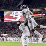 
              Texas A&M offensive lineman Kam Dewberry (75) lifts Texas A&M tight end Donovan Green (18) as they celebrate Green's touchdown against Alabama during the first half of an NCAA college football game Saturday, Oct. 8, 2022, in Tuscaloosa, Ala. (AP Photo/Vasha Hunt)
            