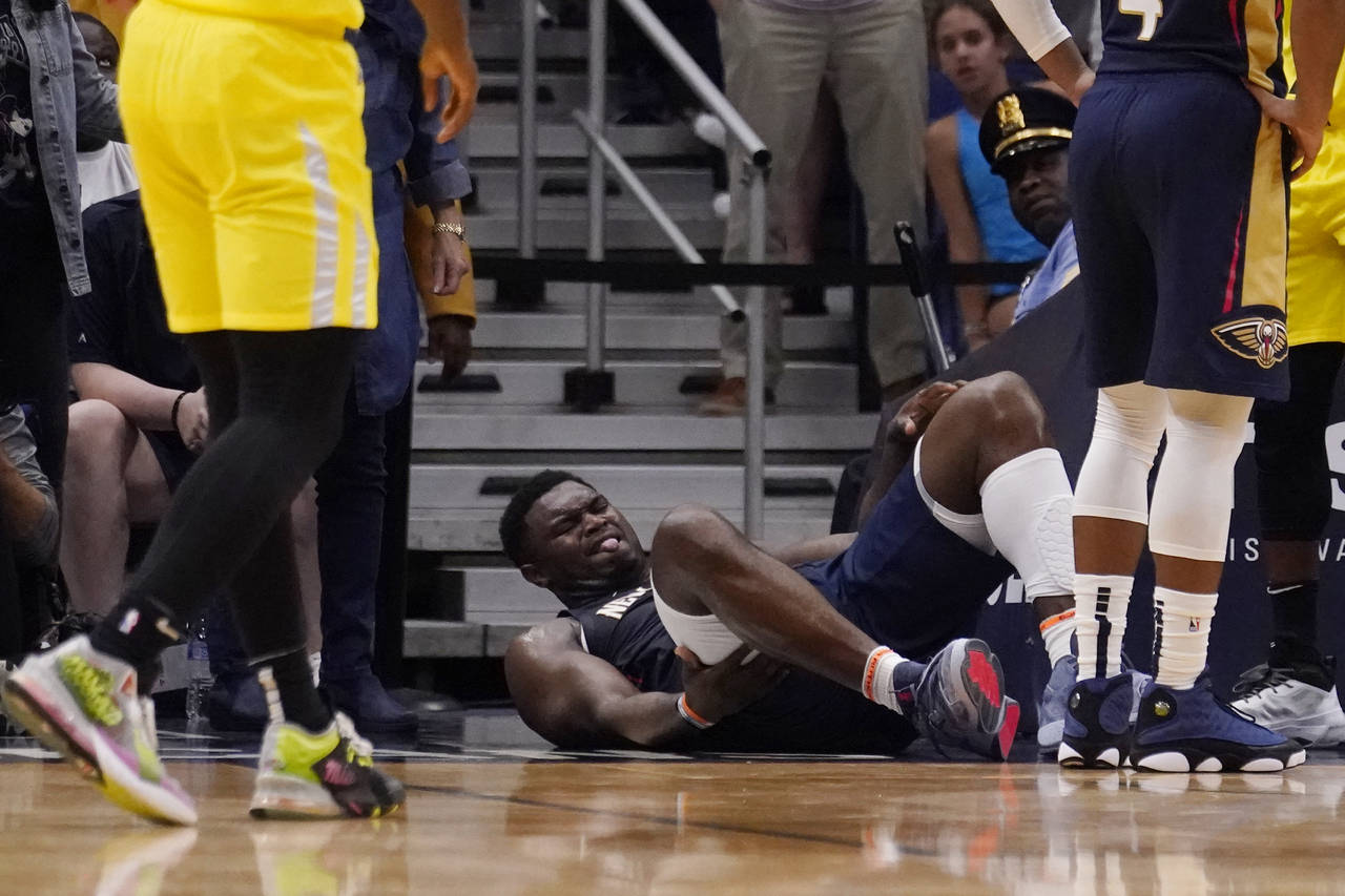 New Orleans Pelicans forward Zion Williamson lies on the ground after going down while driving to t...