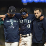 
              Seattle Mariners' Sam Haggerty, center, is helped off the field by training personnel manager Scott Servais, left, while stealing second base during the ninth inning of a baseball game against the Detroit Tigers, Monday, Oct. 3, 2022, in Seattle. The Tigers won 4-3. (AP Photo/Stephen Brashear)
            