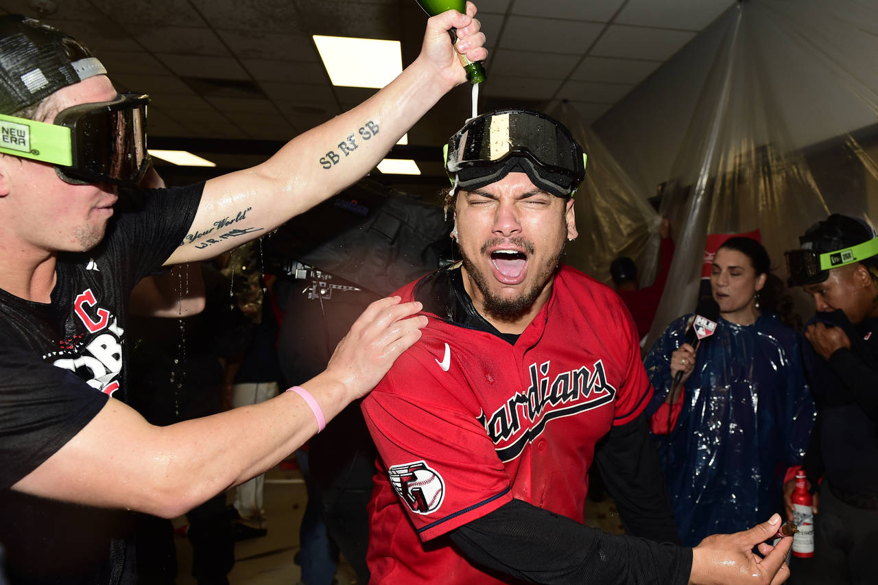 Cleveland Guardians' Josh Naylor, right, is doused as the team celebrates in the clubhouse after de...