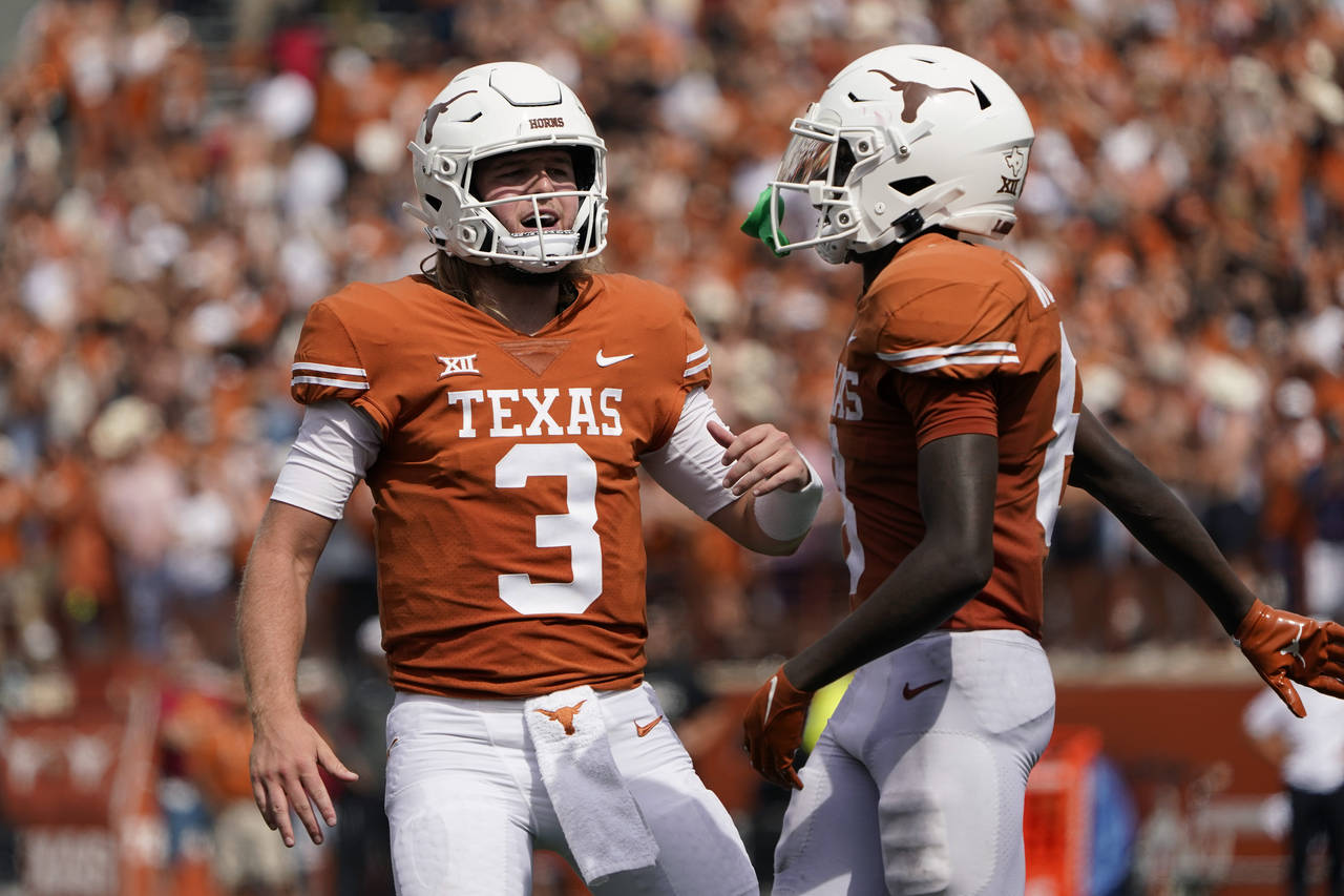 Texas quarterback Quinn Ewers (3) and wide receiver Xavier Worthy (8) celebrate after they connecte...