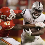 
              Las Vegas Raiders running back Josh Jacobs runs with the ball as Kansas City Chiefs linebacker Darius Harris (47) defends during the second half of an NFL football game Monday, Oct. 10, 2022, in Kansas City, Mo. (AP Photo/Charlie Riedel)
            