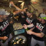 
              Atlanta Braves players celebrate in the club house after they clinched their fifth consecutive NL East title by defeating the Miami Marlins 2-1, in a baseball game, Tuesday, Oct. 4, 2022, in Miami. (AP Photo/Wilfredo Lee)
            