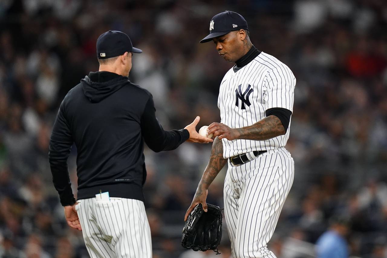 New York Yankees relief pitcher Aroldis Chapman hands the ball to manager Aaron Boone during the ei...