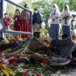 
              Victims' shoes left near one of the gates of Kanjuruhan Stadium, the site of Saturday's soccer stampede, are seen sprinkled with flowers in Malang, East Java, Indonesia, Tuesday, Oct. 4, 2022. Police firing tear gas inside the stadium on Saturday in an attempt to stop violence after an Indonesian soccer match triggered a disastrous crush of fans making a panicked, chaotic run for the exits, leaving at more than 100 people dead, most of them trampled upon or suffocated. (AP Photo/Dicky Bisinglasi)
            