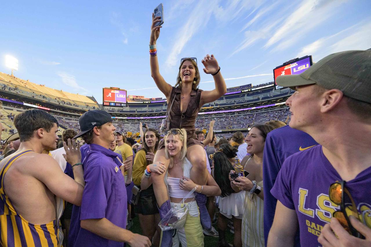 Fans celebrate after they came onto the field after LSU defeated Mississippi in an NCAA college foo...