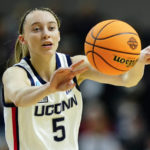 
              FILE - Connecticut guard Paige Bueckers (5) passes the ball during the first quarter of an NCAA college basketball game against Indiana in the Sweet Sixteen of the NCAA women's tournament on March 26, 2022, in Bridgeport, Conn. The injured star says she plans to spend this season as a student coach for the Huskies; she will miss the entire 2022-23 season with a torn ACL in her left knee. (AP Photo/Frank Franklin II, File)
            