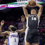 
              San Antonio Spurs forward Isaiah Roby (18) grabs a rebound away from Philadelphia 76ers guard James Harden (1) in the first half of an NBA basketball game, Saturday, Oct. 22, 2022, in Philadelphia. (AP Photo/Laurence Kesterson)
            