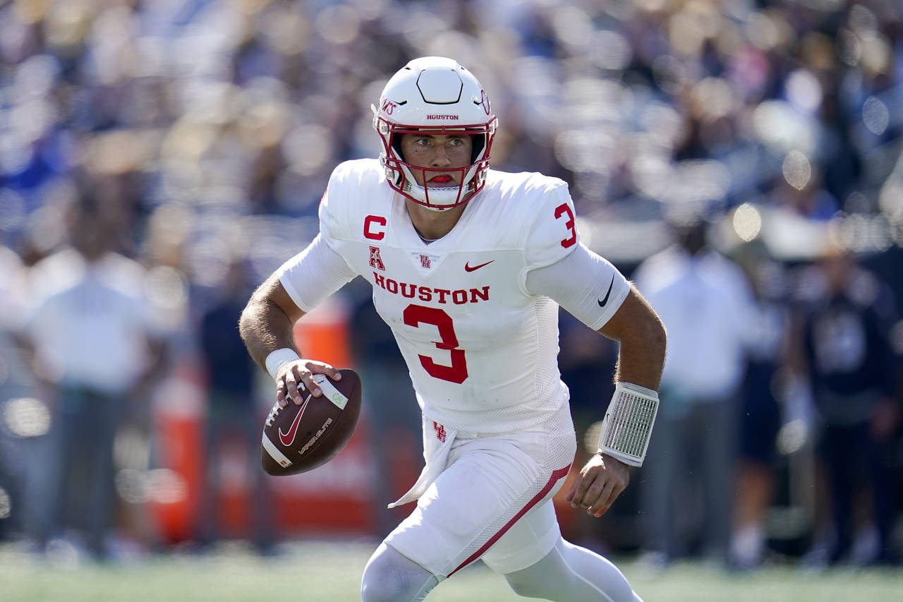 Houston quarterback Clayton Tune rolls out looking to pass against Navy during the first half of an...