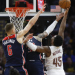 
              Cleveland Cavaliers guard Donovan Mitchell (45) shoots against Washington Wizards center Kristaps Porzingis (6) and forward Kyle Kuzma (33) during overtime of an NBA basketball game, Sunday, Oct. 23, 2022, in Cleveland. (AP Photo/Ron Schwane)
            