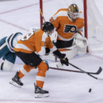 
              Philadelphia Flyers left wing Noah Cates (49) and goaltender Felix Sandstrom (32) try to keep the puck away from San Jose Sharks center Nico Sturm (7) during the first period of an NHL hockey game, Sunday, Oct. 23, 2022, in Philadelphia. (AP Photo/Laurence Kesterson)
            