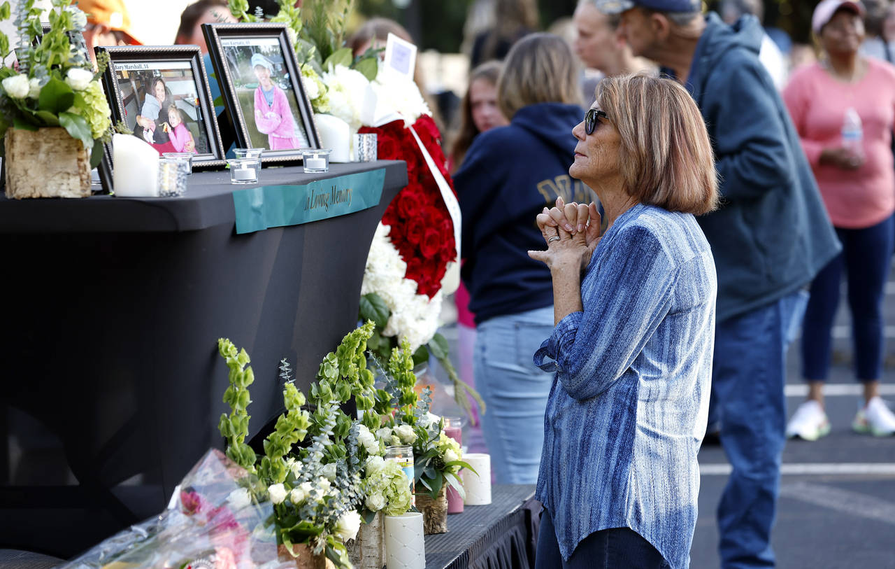 A woman stands before a photo of Raleigh shooting victim Susan Karnatz at a makeshift memorial at t...