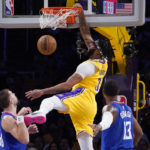 
              Los Angeles Lakers forward Anthony Davis, center, dunks as Los Angeles Clippers center Ivica Zubac, left, and guard Paul George defend during the first half of an NBA basketball game Thursday, Oct. 20, 2022, in Los Angeles. (AP Photo/Mark J. Terrill)
            