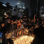 
              Indonesian soccer fans chant slogans during a candle light vigil for the victims of Saturday's soccer riots, in Jakarta, Indonesia, Sunday, Oct. 2, 2022. Panic and a chaotic run for exits after police fired tear gas at an Indonesian soccer match in East Java to drive away fans upset with their team's loss left a large number of people dead, most of whom were trampled upon or suffocated. (AP Photo/Dita Alangkara)
            