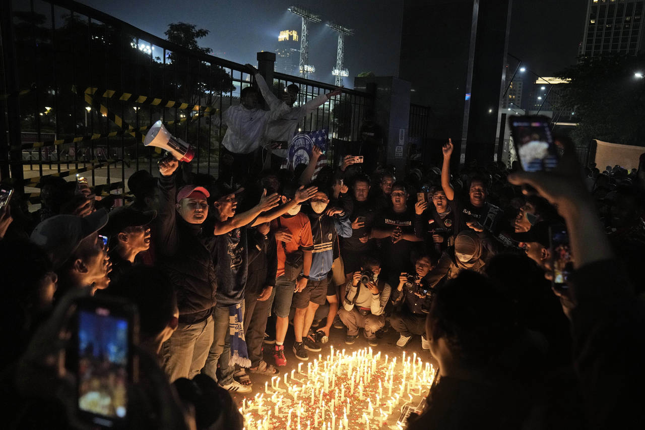 Indonesian soccer fans chant slogans during a candle light vigil for the victims of Saturday's socc...