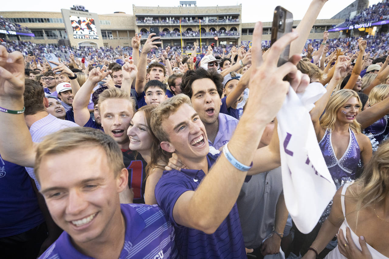 TCU fans celebrate on the field after their team defeated Oklahoma State in double overtime of an N...