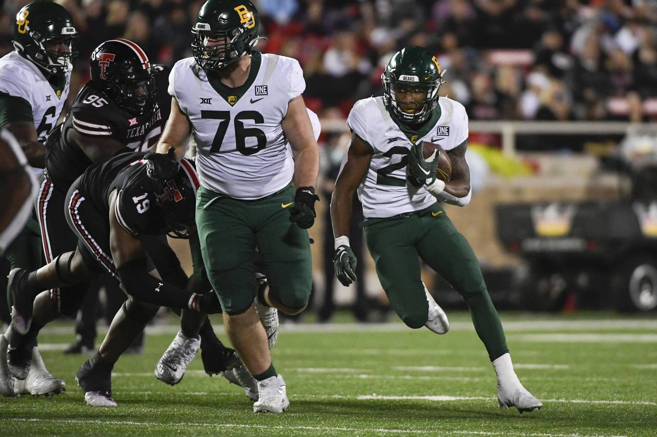 Baylor running back Richard Reese, right, runs the ball against Texas Tech during the second half o...