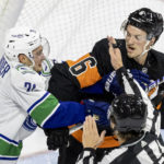 
              Vancouver Canucks left wing Nils Hoglander (21) and Philadelphia Flyers defenseman Travis Sanheim (6) fight during the second period of an NHL hockey game, Saturday, Oct. 15, 2022, in Philadelphia. (AP Photo/Laurence Kesterson)
            