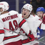 
              Carolina Hurricanes' Jesper Fast (71), of Sweden, celebrates his goal with Jordan Martinook (48) as Vancouver Canucks' Kyle Burroughs (44) skates to the bench during the third period of an NHL hockey game in Vancouver, British Columbia, Monday, Oct. 24, 2022. (Darryl Dyck/The Canadian Press via AP)
            