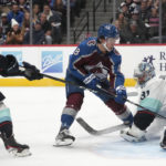 
              Colorado Avalanche center Alex Newhook, middle, has his shot stopped by Seattle Kraken goaltender Philipp Grubauer, right, after driving past defenseman Vince Dunn during the first period of an NHL hockey game Friday, Oct. 21, 2022, in Denver. (AP Photo/David Zalubowski)
            