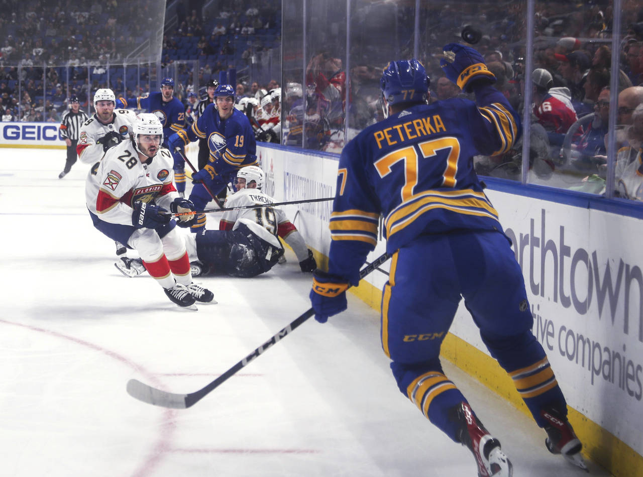 Florida Panthers and Buffalo Sabres players watch as the puck flies past Sabres' JJ Peterka during ...