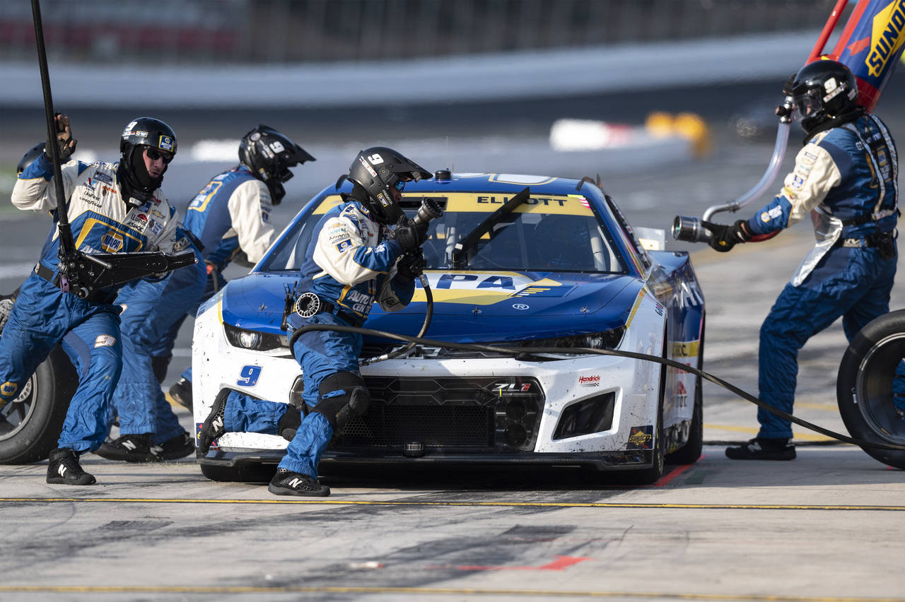 The pit crew of Chase Elliott (9) race to complete a pit stop during a NASCAR Cup Series auto race ...