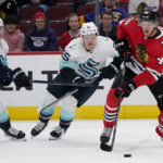 
              Chicago Blackhawks defenseman Filip Roos, right, controls the puck against Seattle Kraken center Morgan Geekie, left, and center Karson Kuhlman during the first period of an NHL hockey game in Chicago, Sunday, Oct. 23, 2022. (AP Photo/Nam Y. Huh)
            