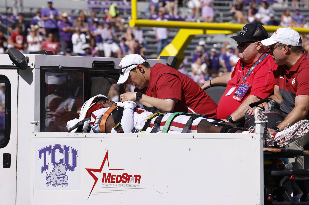 Oklahoma defensive back Damond Harmon (17) is tended to by team staff after a collision on a play a...