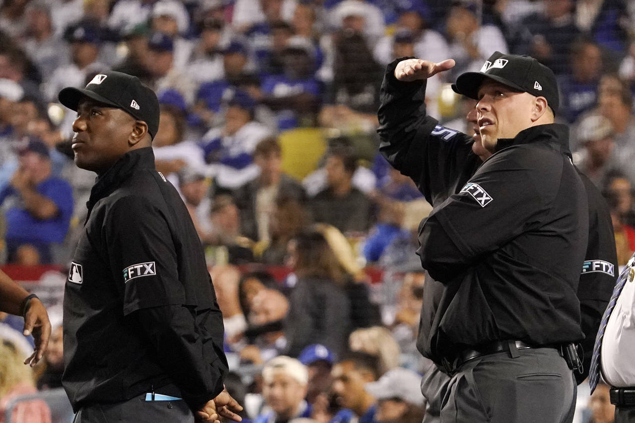 Umpires look toward the sky after a drone was seen above the field during the third inning of a bas...