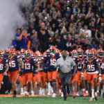 
              FILE - Syracuse head coach Dino Babers, center, leads his team on to the field before an NCAA college football game against Virginia on Friday, Sept. 23, 2022 in Syracuse, N.Y. Syracuse was selected the surprise team in the Associated Press ACC Midseason Awards, Wednesday, Oct. 12, 2022.(AP Photo/Adrian Kraus)
            