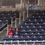 
              Two Washington Nationals fans sit and watch the game against the Atlanta Braves surrounded by empty seats during the ninth inning of a baseball game at Nationals Park, Tuesday, Sept. 27, 2022, in Washington. The Braves won 8-2. (AP Photo/Jess Rapfogel)
            