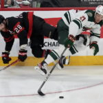 
              Minnesota Wild right wing Brandon Duhaime reaches for the puck as he collides with Ottawa Senators right wing Claude Giroux during the third period of an NHL hockey game, Thursday, Oct. 27, 2022 in Ottawa, Ontario. (Adrian Wyld/The Canadian Press via AP)
            