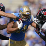 
              UCLA running back Zach Charbonnet (24) is tackled by Utah safety R.J. Hubert (11) and cornerback Zemaiah Vaughn (16) during the first half of an NCAA college football game in Pasadena, Calif., Saturday, Oct. 8, 2022. (AP Photo/Ashley Landis)
            