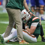
              Miami quarterback Tyler Van Dyke (9) is helped on the field after he fumbled the ball as he was taken down by Duke linebacker Cam Dillon and defensive back Darius Joiner during the first half of an NCAA college football game, Saturday, Oct. 22, 2022, in Miami Gardens, Fla. (AP Photo/Wilfredo Lee)
            
