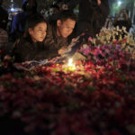 
              People lay flowers during a candle light vigil for the victims of Saturday's soccer riots outside Kanjuruhan Stadium where it broke out, in Malang, East Java, Indonesia, Sunday, Oct. 2, 2022. Police firing tear gas after an Indonesian soccer match in an attempt to stop violence triggered a disastrous crush of fans making a panicked, chaotic run for the exits, leaving a large number of people dead, most of them trampled upon or suffocated. (AP Photo/Trisnadi)
            