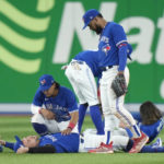 
              Toronto Blue Jays cener fielder George Springer, bottom, lies on the field as teammates try to help him after he collided with Bo Bichette while trying to catch a short fly ball during the eighth inning of Game 2 of a baseball AL wild-card playoff series against the Seattle Mariners, Saturday, Oct. 8, 2022, in Toronto. (Frank Gunn/The Canadian Press via AP)
            