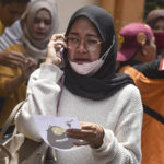 
              A women makes a phone call as she holds a picture of a victim of a soccer stampede provided by volunteers for identification purpose, at a hospital in Malang, East Java, Indonesia, Sunday, Oct. 2, 2022. Panic at an Indonesian soccer match Saturday left a number of people dead, most of whom were trampled to death after police fired tear gas to prevent violence. (AP Photo/Dicky Bisinglasi)
            