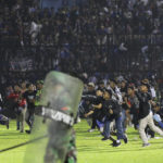 
              Soccer fans enter the pitch during a clash between supporters at Kanjuruhan Stadium in Malang, East Java, Indonesia, Saturday, Oct. 1, 2022. Panic following police actions left over 100 dead, mostly trampled to death, police said Sunday. (AP Photo/Yudha Prabowo)
            